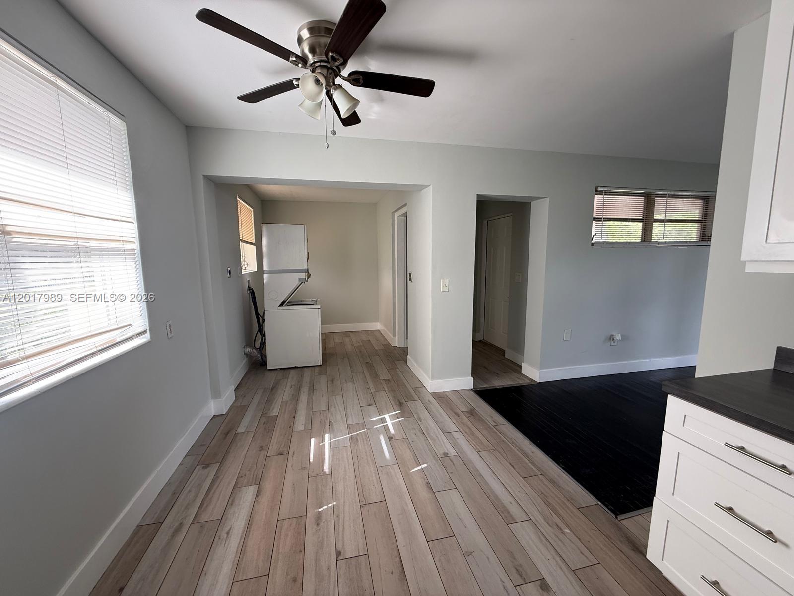 A room with light wood-look flooring, a ceiling fan, and a laundry area in back — 4393 Davis Rd # 1, Lake Worth FL 33461, LAKE WORTH, FL