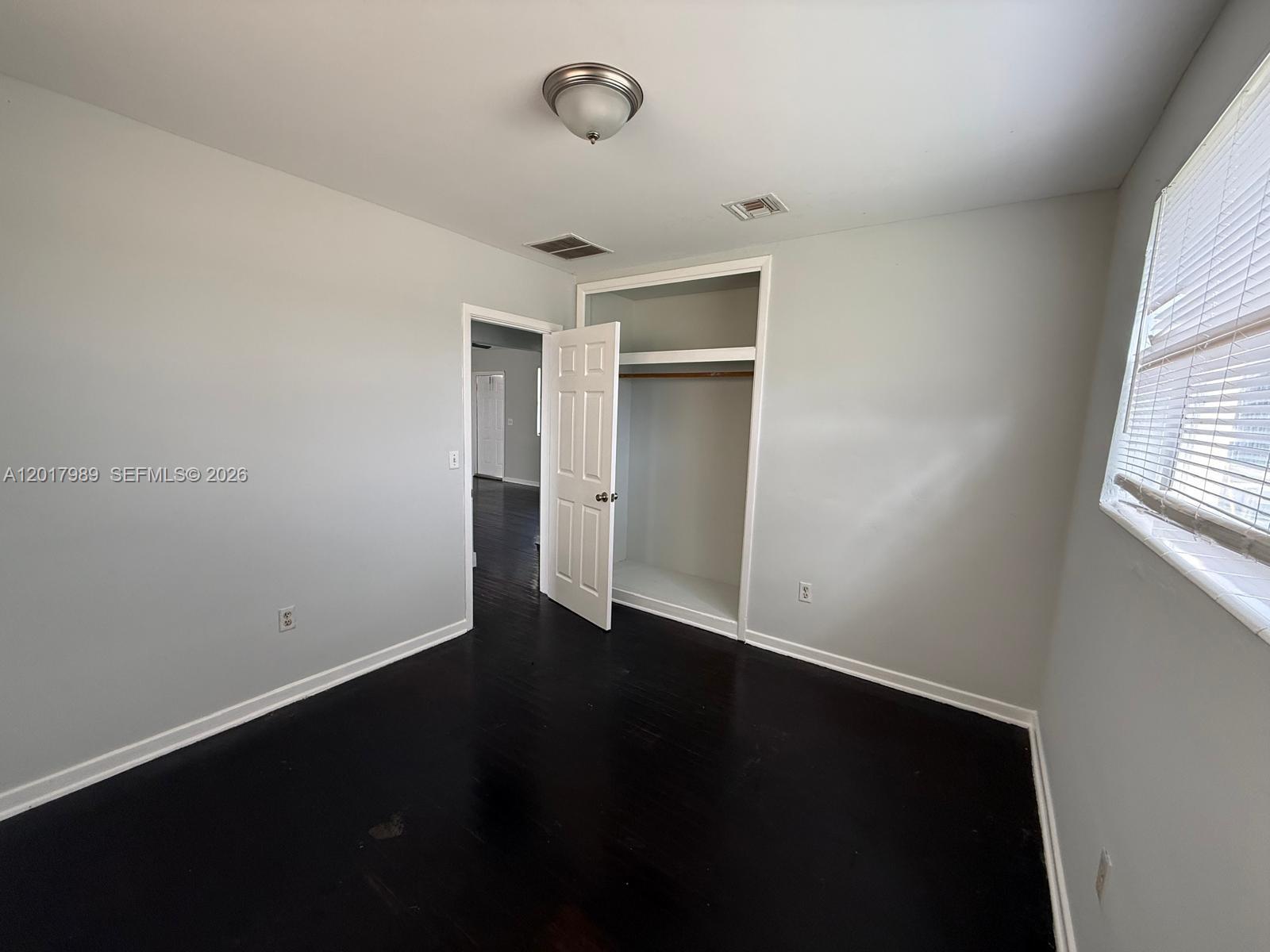 A bedroom features dark hardwood floors, light gray walls, a closet, and a window — 4393 Davis Rd # 1, Lake Worth FL 33461, LAKE WORTH, FL