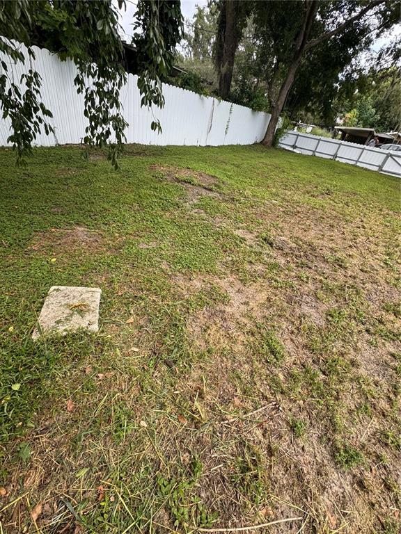 A grassy backyard features a white vinyl fence and a concrete stepping stone — KEUKA AVENUE, LEESBURG, FL