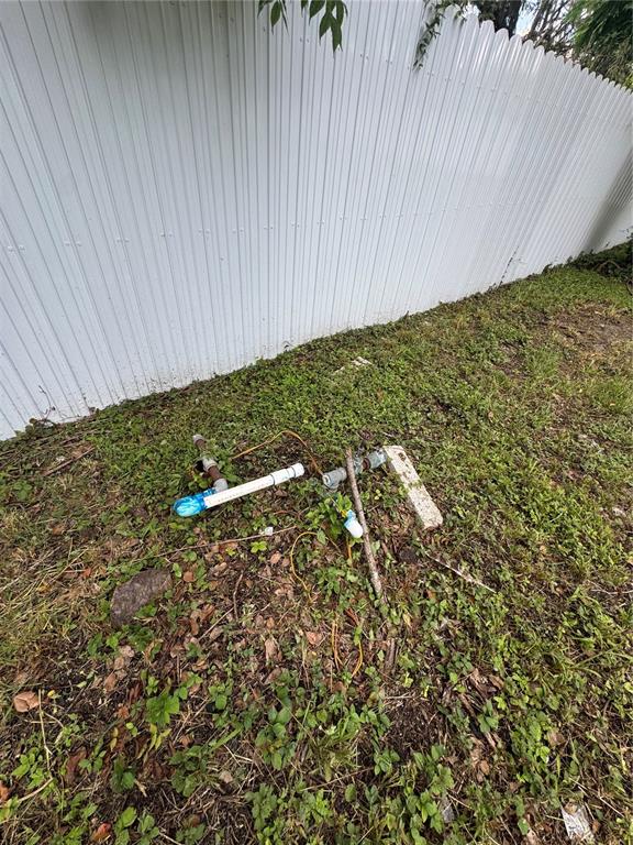 Exposed irrigation pipes and wiring sit on the ground next to a white metal fence — KEUKA AVENUE, LEESBURG, FL