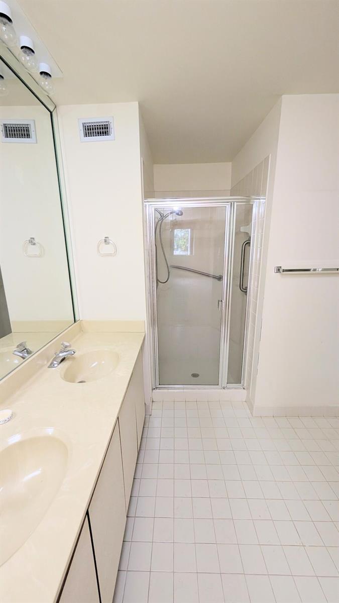 A bathroom features a double vanity with a beige countertop and a glass-enclosed walk-in shower — 9746 Nickels Boulevard # 104, Boynton Beach FL 33436, BOYNTON BEACH, FL