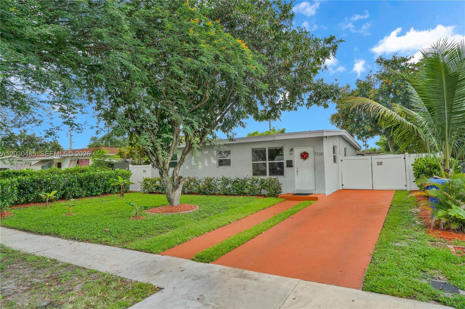 A single-story house with a gray exterior, a red driveway, and a large front tree — 7220 Arthur St, Hollywood FL 33024, HOLLYWOOD, FL