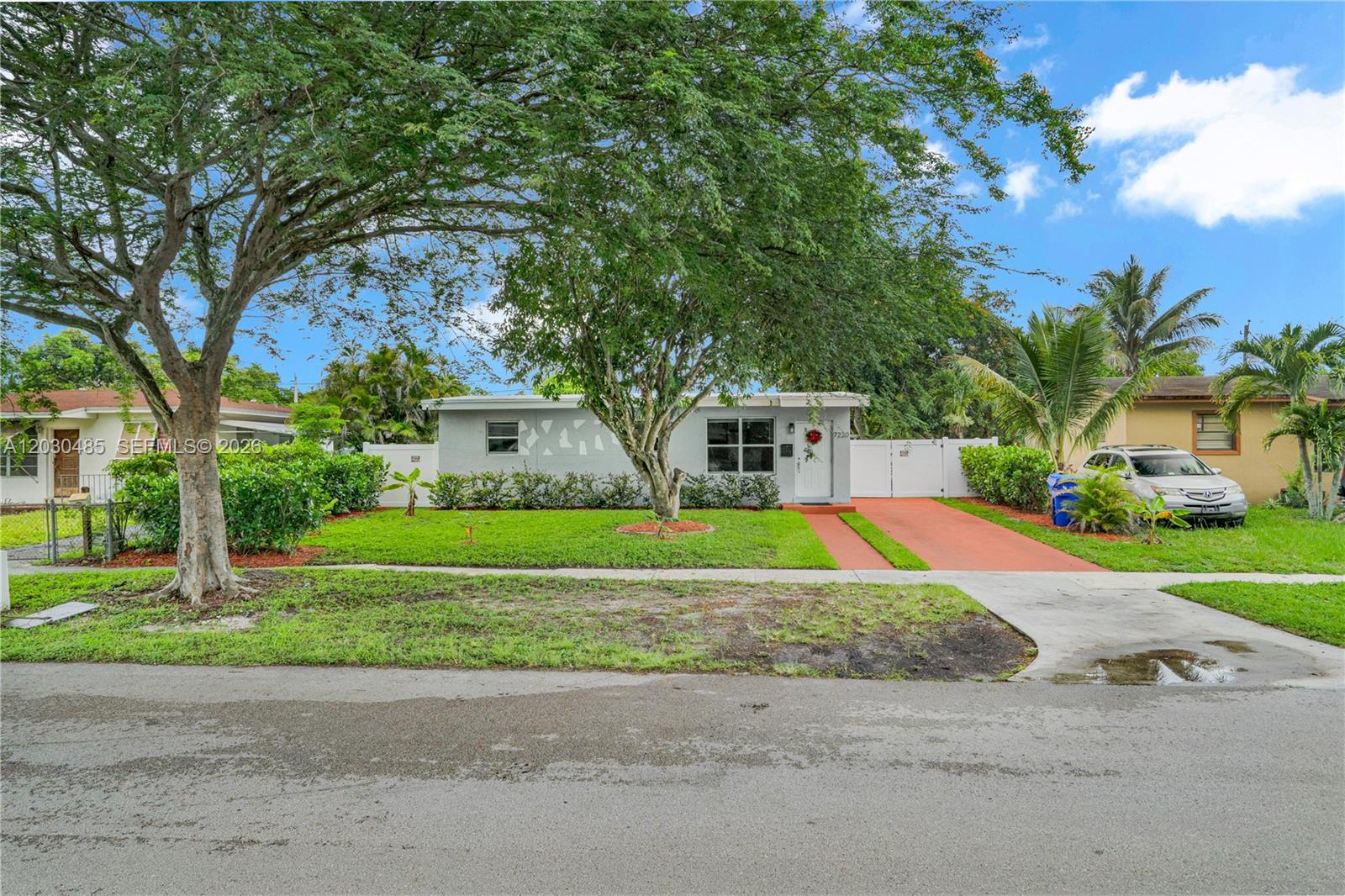 A single-story gray house features a front lawn, a large tree, and a paved driveway — 7220 Arthur St, Hollywood FL 33024, HOLLYWOOD, FL