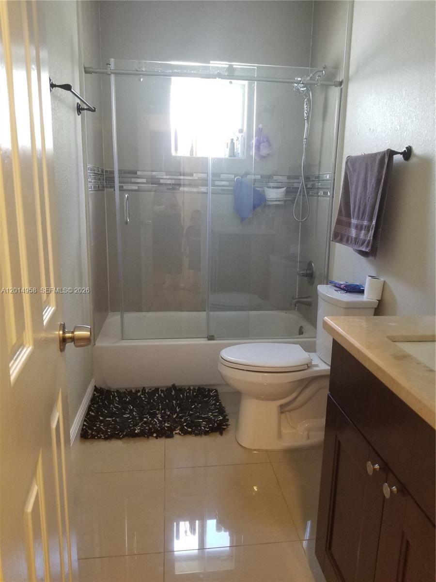 A bathroom features a glass-enclosed tub shower, a white toilet, and a dark wood vanity — 1935 NW 96th St, Miami FL 33147, MIAMI, FL
