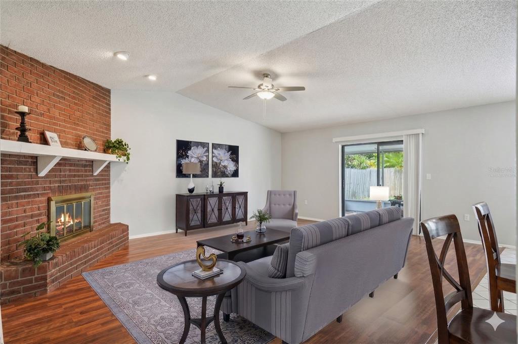 A kitchen with light wood cabinets, granite countertops, and a black range hood overlooks a dining area — 105 LOTUS CIRCLE, SAFETY HARBOR, FL