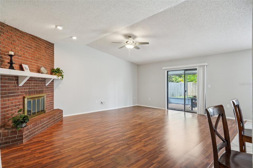 A grassy backyard features a screened-in patio and a tall wooden privacy fence — 105 LOTUS CIRCLE, SAFETY HARBOR, FL