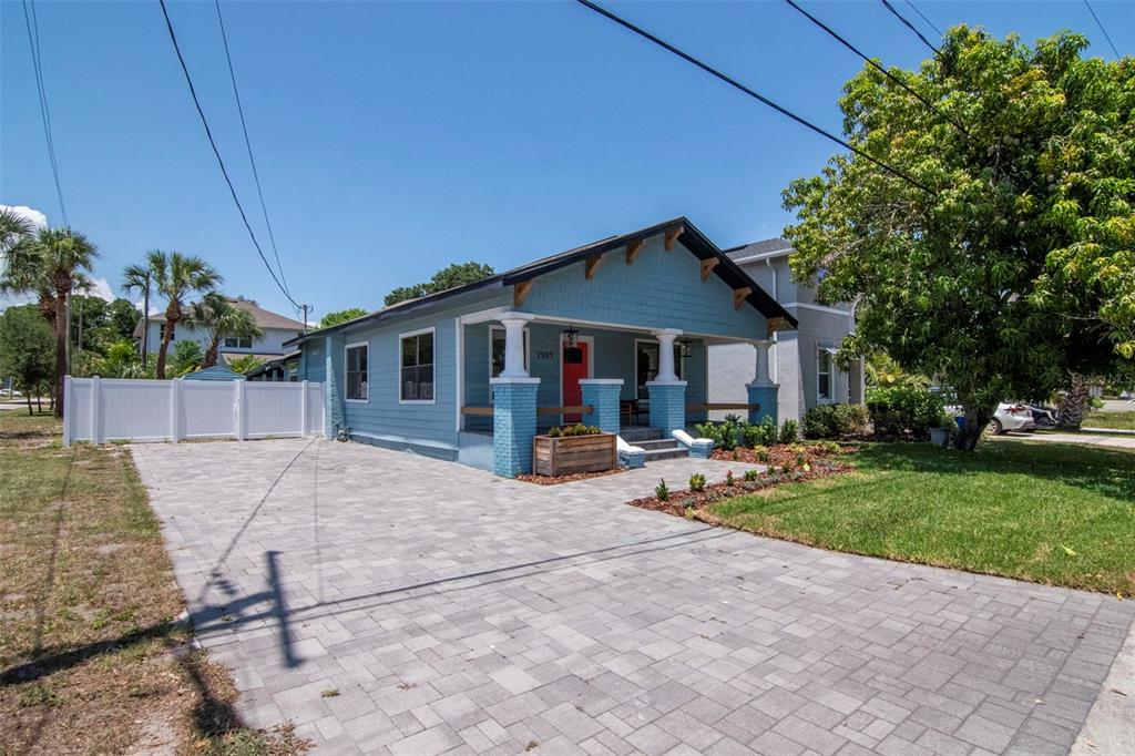 A blue bungalow with a front porch and a paved driveway sits on a lawn — 2507 W GRAY STREET, TAMPA, FL