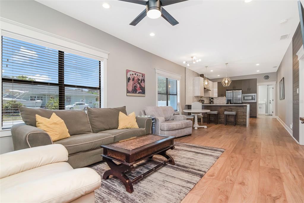 An open-concept living room and kitchen featuring hardwood floors, a gray sofa, and recessed lighting — 2507 W GRAY STREET, TAMPA, FL