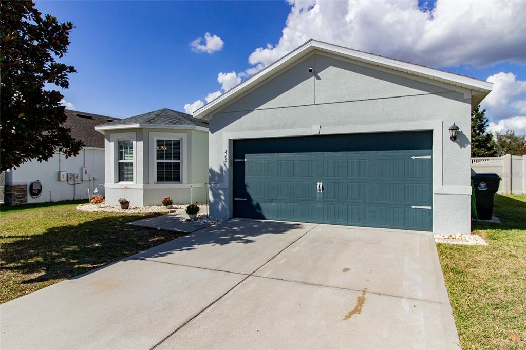 A single-story house with a teal garage door, a bay window, and a concrete driveway — 408 CEDAR GLEN DRIVE, LAKE ALFRED, FL