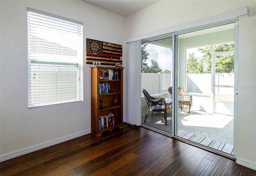 A room with dark wood flooring, a wooden bookshelf, and a sliding glass door to a lanai — 408 CEDAR GLEN DRIVE, LAKE ALFRED, FL