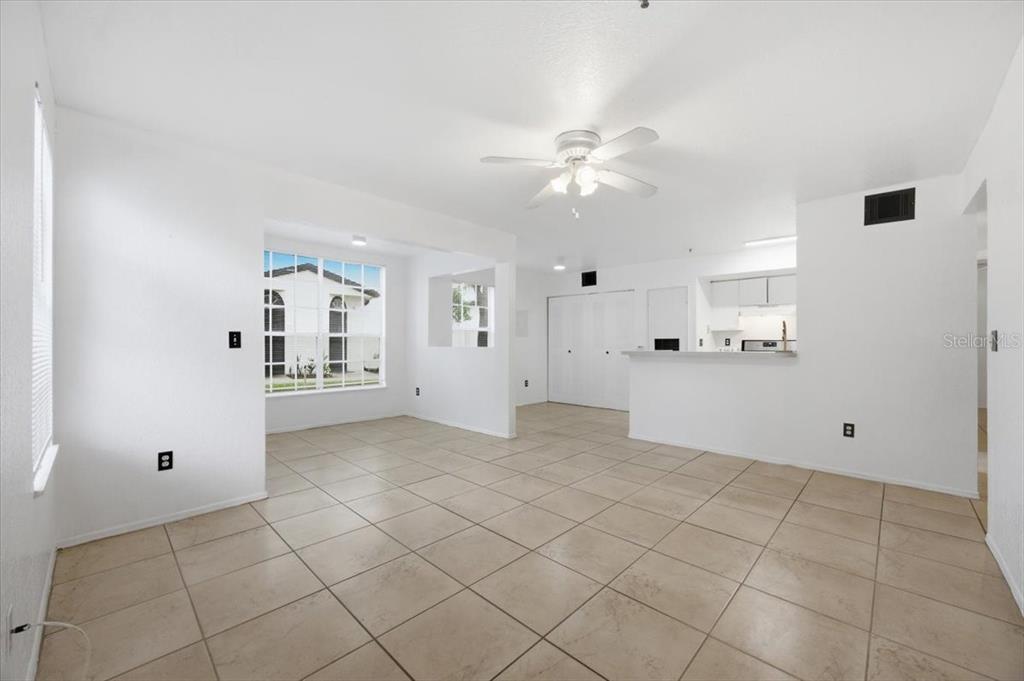 An open-concept living and dining area features white walls, tile flooring, and a ceiling fan — 1602 COLUMBIA ARMS CIRCLE UNIT 106, KISSIMMEE, FL