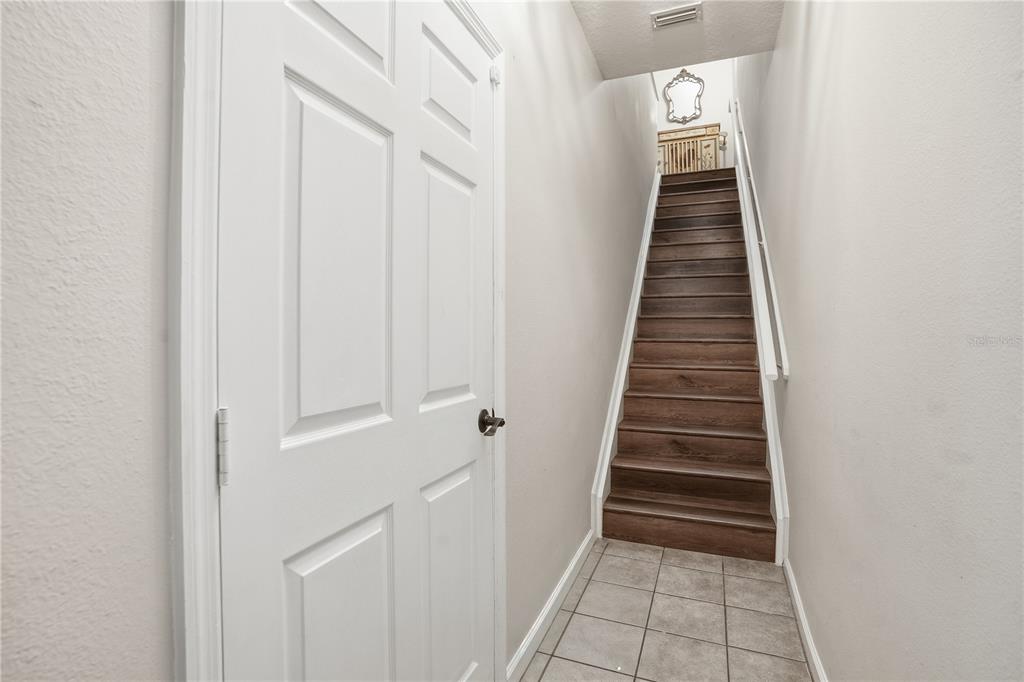 A white door stands next to a staircase with dark wood treads and tile flooring — 815 S FORT HARRISON AVENUE, CLEARWATER, FL