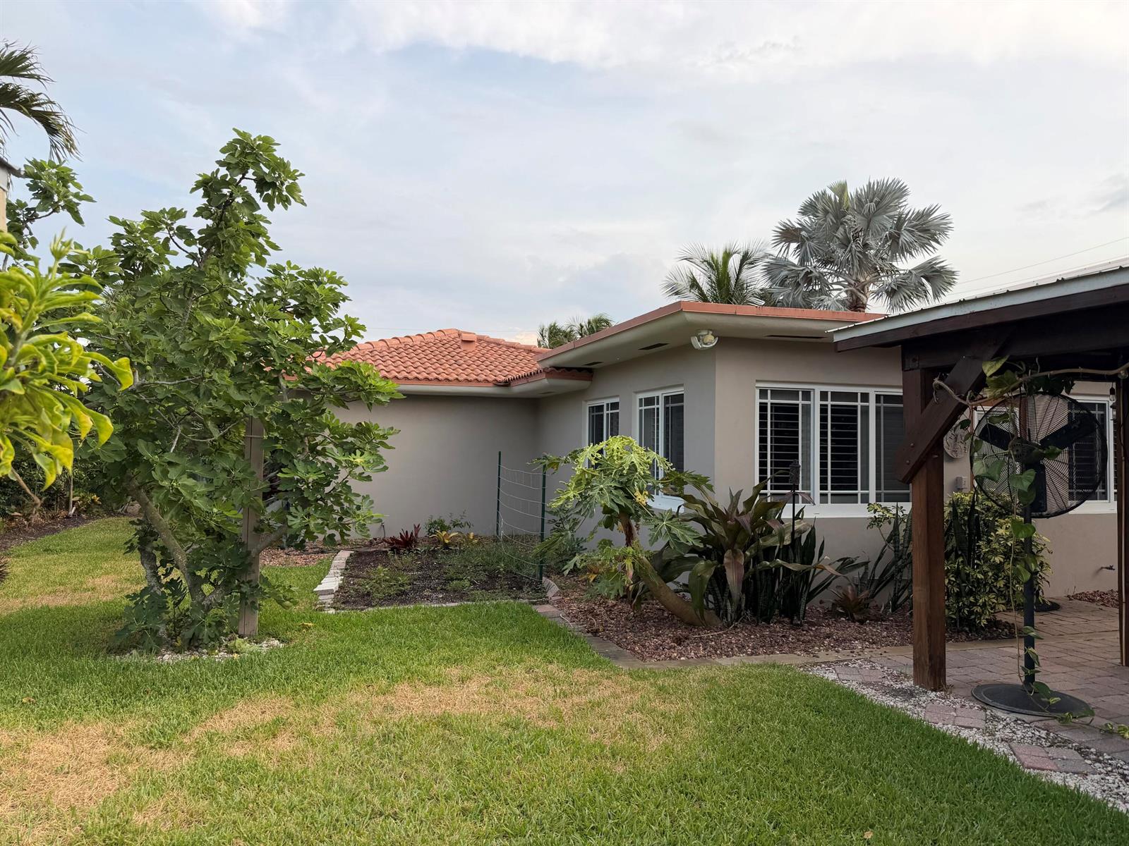 A beige house with a red tile roof features a garden and a covered patio — 1140 Morse Boulevard, Singer Island FL 33404, SINGER ISLAND, FL
