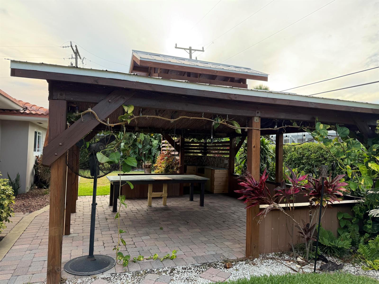 An outdoor covered patio features a dining table, a built-in kitchen area, and a fan — 1140 Morse Boulevard, Singer Island FL 33404, SINGER ISLAND, FL