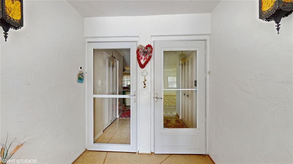 A white entryway features two glass-paneled storm doors and two decorative wall-mounted lanterns — 1655 S HIGHLAND AVENUE UNIT D238, CLEARWATER, FL
