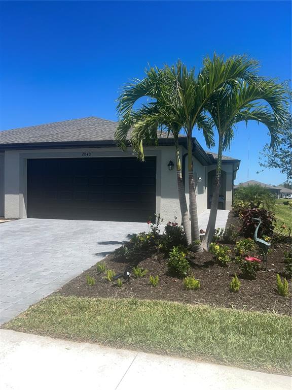 A single-story house exterior features a dark garage door, a paved driveway, and palm trees — 2040 MACKEREL STREET, PORT CHARLOTTE, FL
