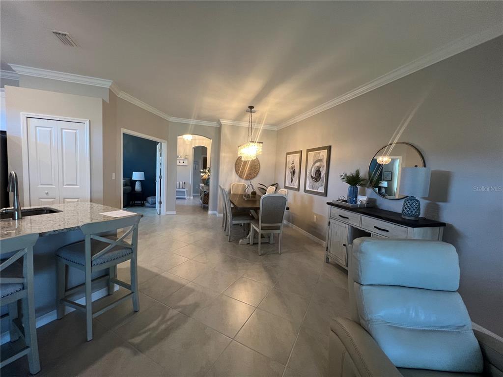 A dining area with a chandelier, table, chairs, and a sideboard sits near a kitchen — 2040 MACKEREL STREET, PORT CHARLOTTE, FL