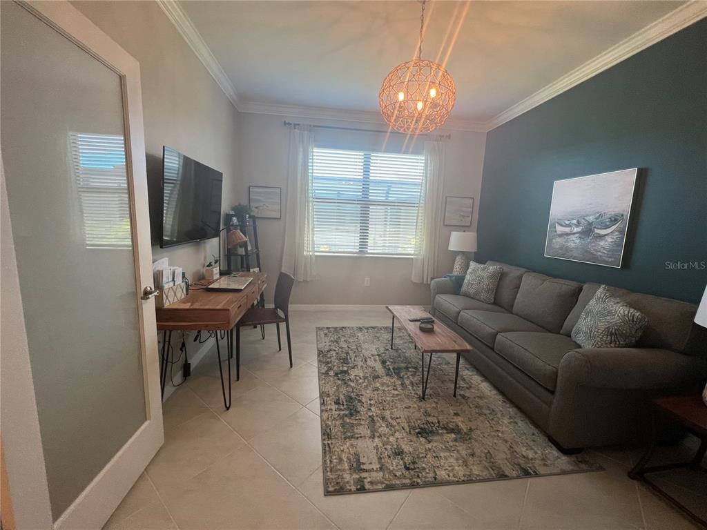 A home office features a desk, a gray sofa, and a dark blue accent wall — 2040 MACKEREL STREET, PORT CHARLOTTE, FL