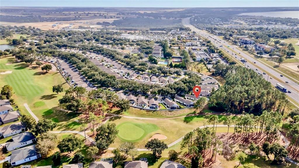 An aerial view shows a residential neighborhood bordering a golf course next to a highway — 2067 BRAXTON STREET, CLERMONT, FL