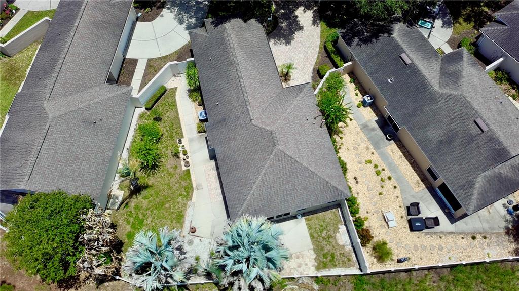 An aerial view shows three adjacent houses with gray shingled roofs and fenced backyards — 2067 BRAXTON STREET, CLERMONT, FL