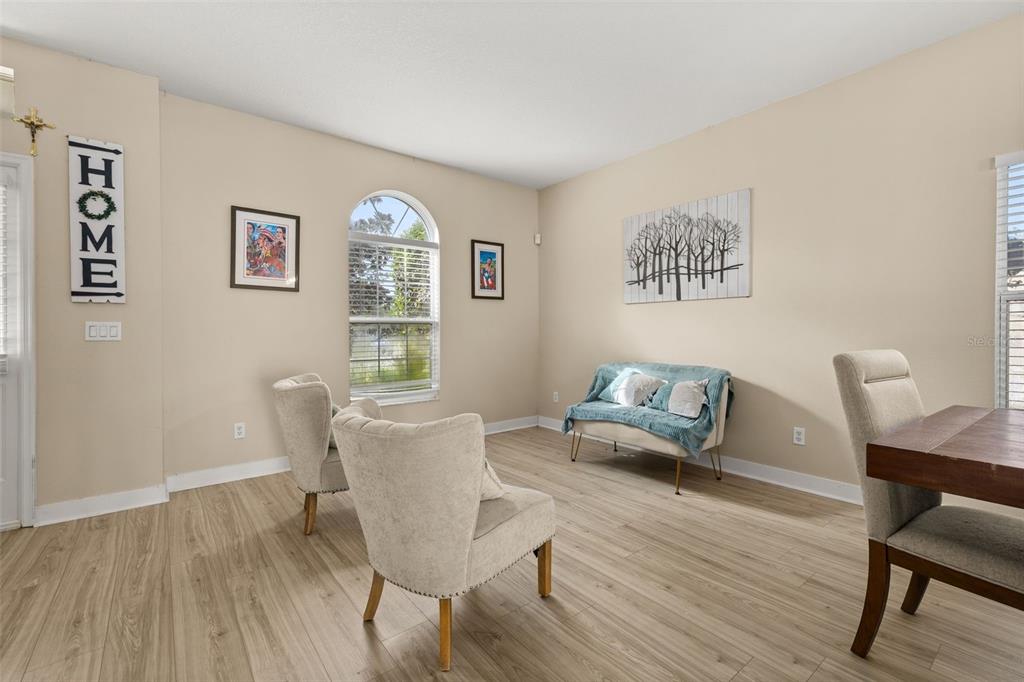 A living room features light wood-look flooring, two beige armchairs, and a small upholstered bench — 1404 SWAINSON COURT, ORLANDO, FL