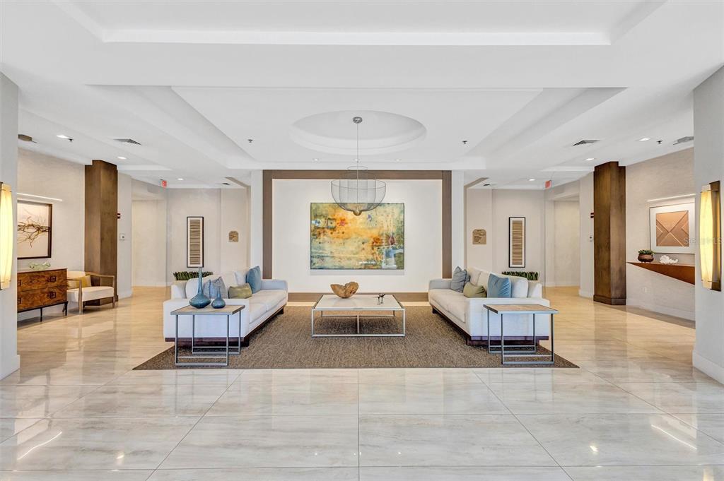 A modern lobby features white marble floors, two sofas, a central coffee table, and artwork — 3060 GRAND BAY BOULEVARD UNIT 174, LONGBOAT KEY, FL