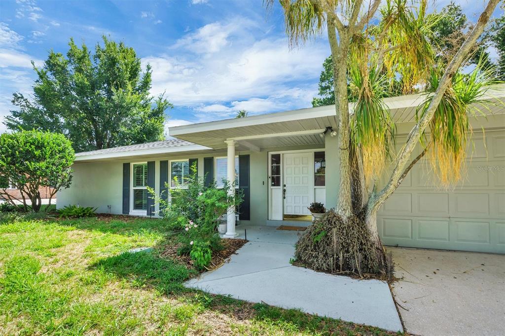 A single-story house with a light gray exterior, a white front door, and a palm tree — 136 LAKE MARIAM ROAD SE, WINTER HAVEN, FL