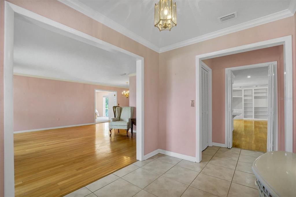A tiled entryway leads to a pink-walled living area with hardwood floors and a chandelier — 136 LAKE MARIAM ROAD SE, WINTER HAVEN, FL