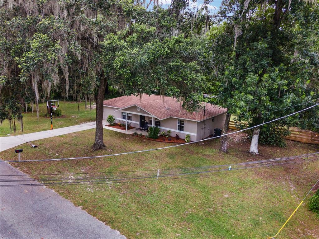 An aerial view of a single-story house with a brown roof surrounded by large trees — 2450 SE 40TH STREET ROAD, OCALA, FL