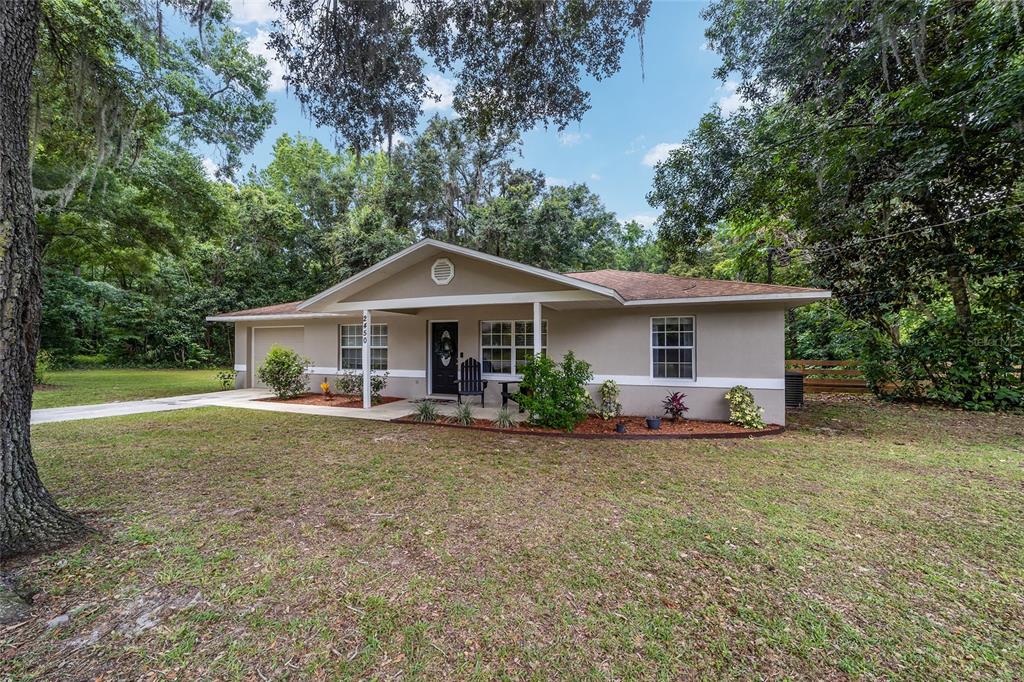 A single-story house with a beige exterior, a front porch, and a concrete driveway — 2450 SE 40TH STREET ROAD, OCALA, FL
