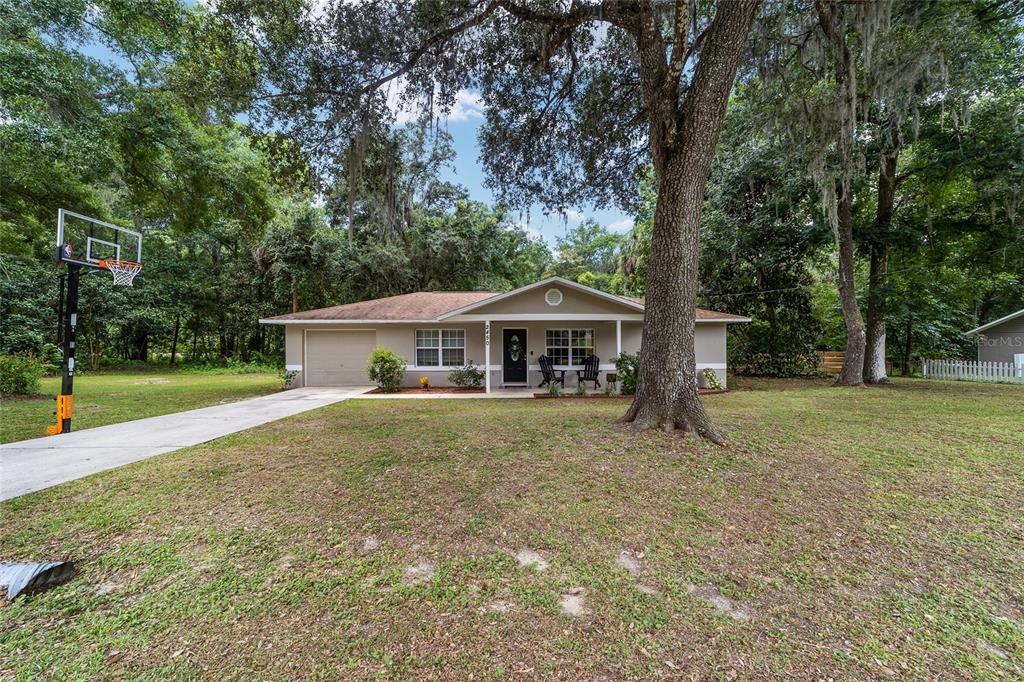 A single-story house with a tan exterior, a front porch, and a basketball hoop nearby — 2450 SE 40TH STREET ROAD, OCALA, FL