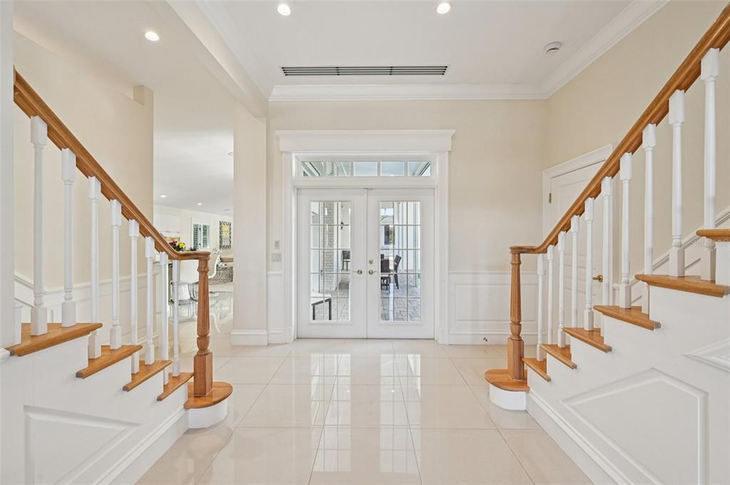 A bright foyer features white tile floors, dual staircases with wooden railings, and glass-paned double doors — 1121 MORNINGSIDE PLACE, SARASOTA, FL