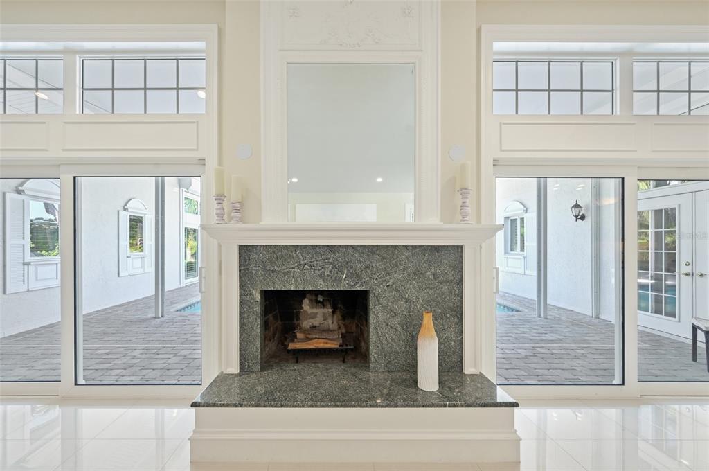 A fireplace with a green stone surround sits between two large glass doors and windows — 1121 MORNINGSIDE PLACE, SARASOTA, FL