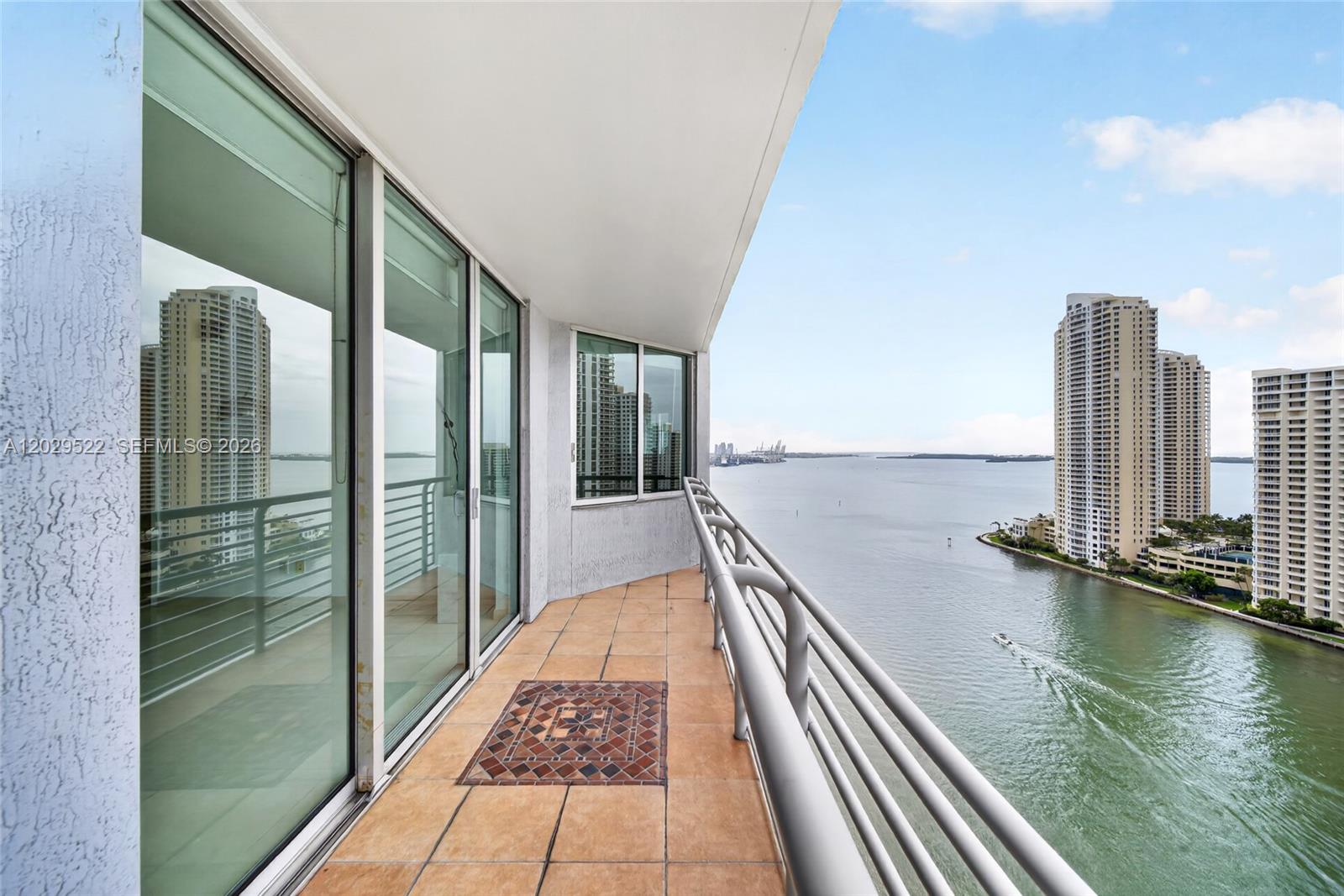 A balcony with tile flooring overlooks a bay with high-rise buildings in the distance — 325 S Biscayne Blvd # 2219, Miami FL 33131, MIAMI, FL