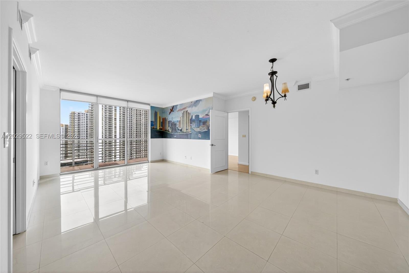 A bright, empty room features white tile floors, a city mural, and a balcony view — 325 S Biscayne Blvd # 2219, Miami FL 33131, MIAMI, FL