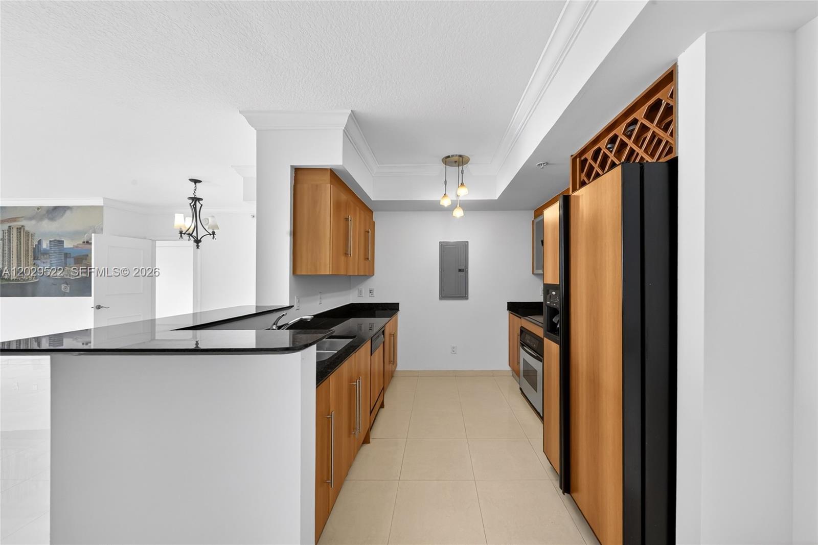 A kitchen features light wood cabinets, black countertops, stainless steel appliances, and tile flooring — 325 S Biscayne Blvd # 2219, Miami FL 33131, MIAMI, FL