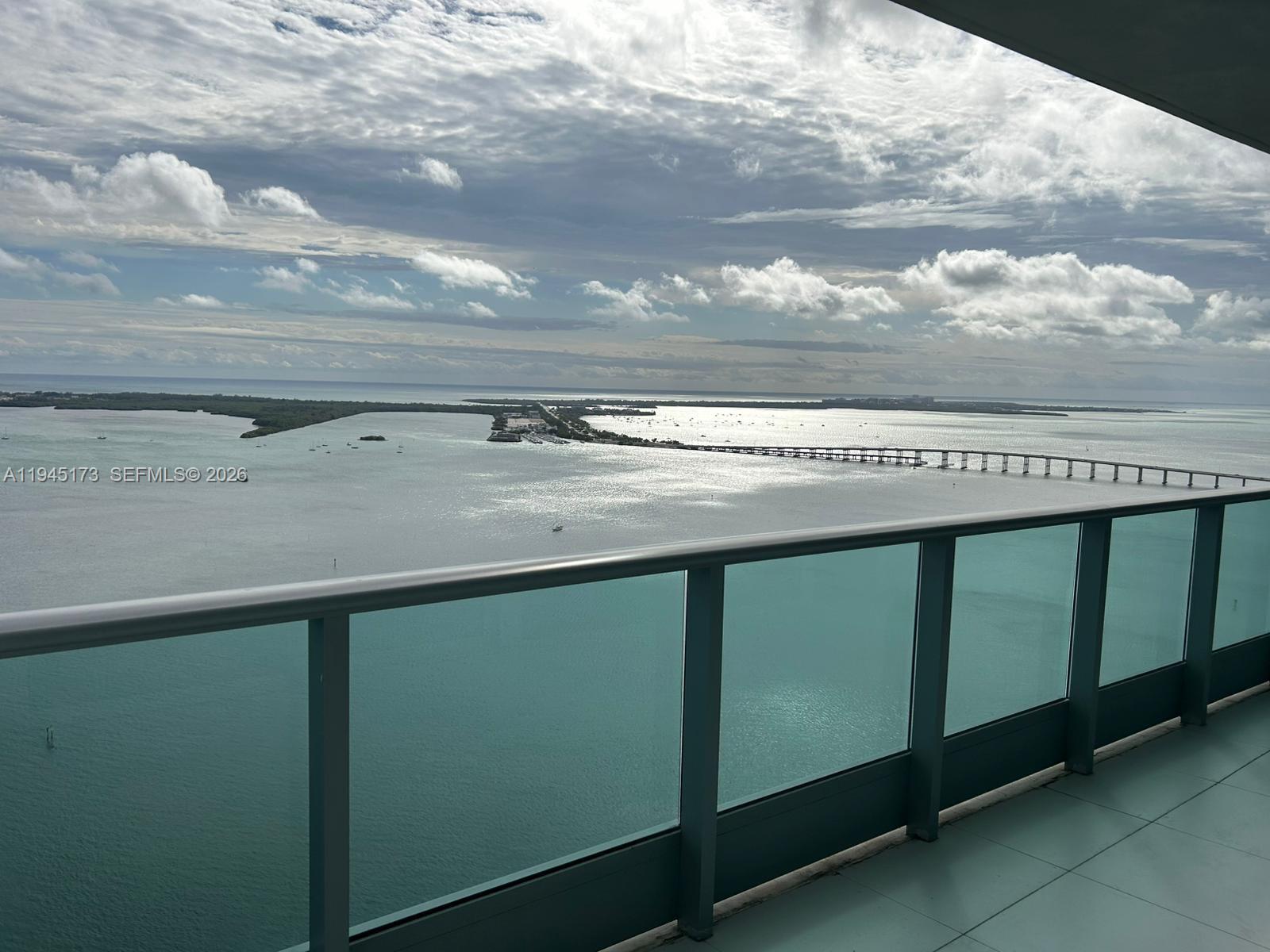 A balcony with a glass railing overlooks a bay and a long bridge — 1331 Brickell Bay Dr # 4107, Miami FL 33131, MIAMI, FL