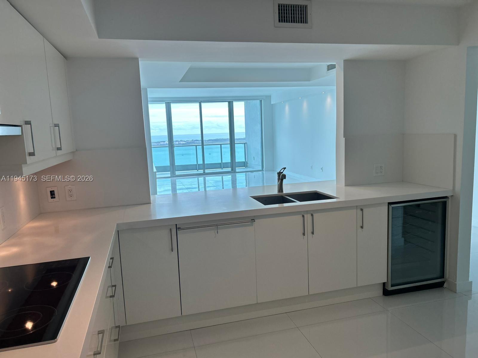 A modern white kitchen features a sink, wine cooler, and a view of the ocean — 1331 Brickell Bay Dr # 4107, Miami FL 33131, MIAMI, FL