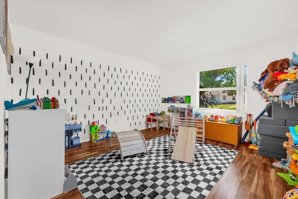 A playroom with a checkered rug, a patterned accent wall, and various children's toys — 623 SWALLOW DRIVE, CASSELBERRY, FL