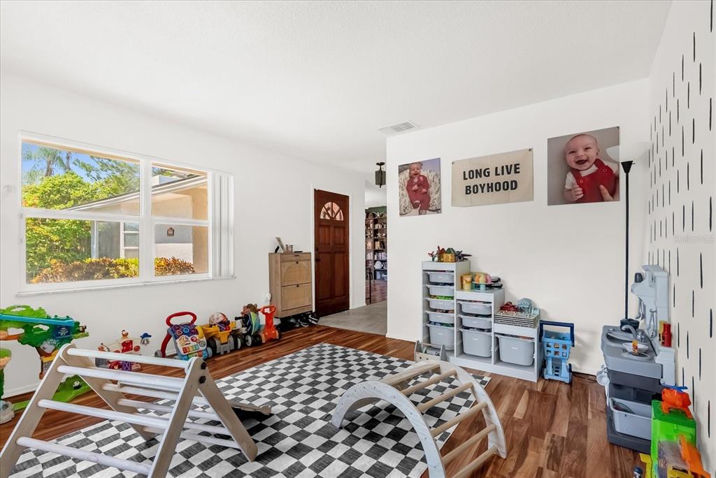 A playroom features a checkered rug, wooden climbing structures, toy storage units, and white walls — 623 SWALLOW DRIVE, CASSELBERRY, FL