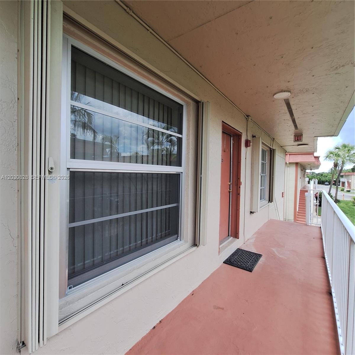 An exterior walkway features a window with accordion shutters, a door, and a metal railing — 12850 SW 43rd Dr # B, Miami FL 33175, MIAMI, FL