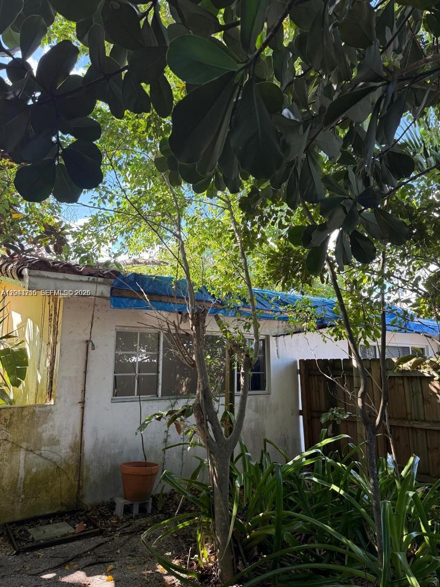 A white exterior wall features a blue tarp covering the roofline above two windows — 5600 SW 74th Ct, Miami FL 33143, MIAMI, FL