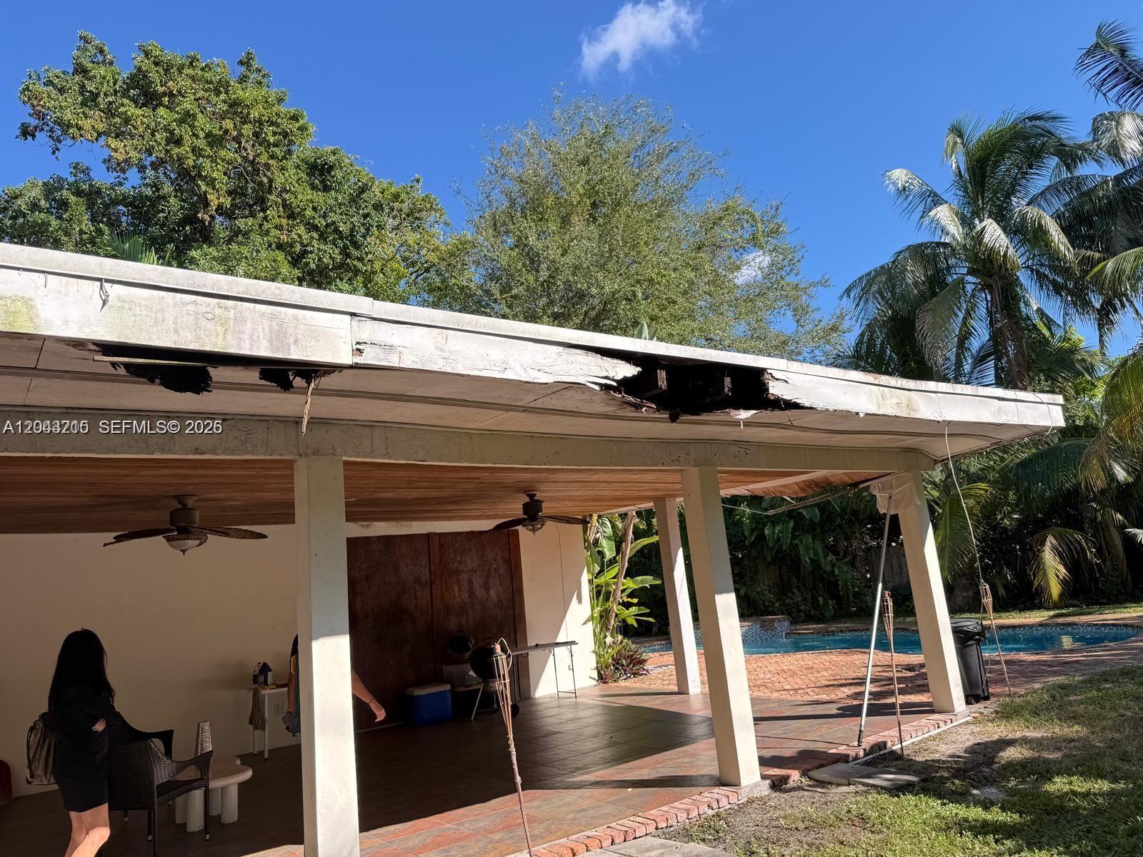 A covered patio features a damaged wooden fascia board along the edge of the roof — 5600 SW 74th Ct, Miami FL 33143, MIAMI, FL