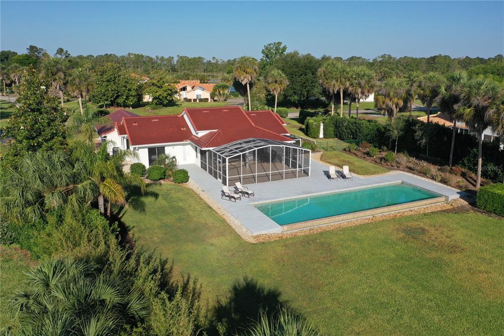 An aerial view of a house with a red roof, screened lanai, and rectangular pool — 13300 SKIING PARADISE BOULEVARD, CLERMONT, FL