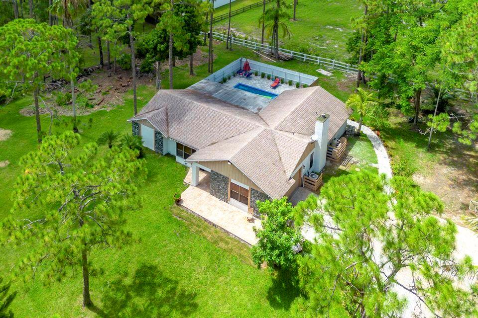 An aerial view shows a single-story house with a fenced pool area and surrounding trees — 15211 60th Place N, Loxahatchee FL 33470, LOXAHATCHEE, FL