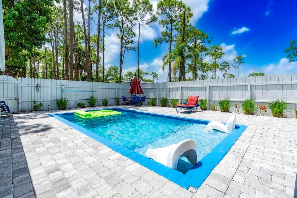 A rectangular swimming pool with a sun shelf and lounge chairs sits on a paved patio — 15211 60th Place N, Loxahatchee FL 33470, LOXAHATCHEE, FL