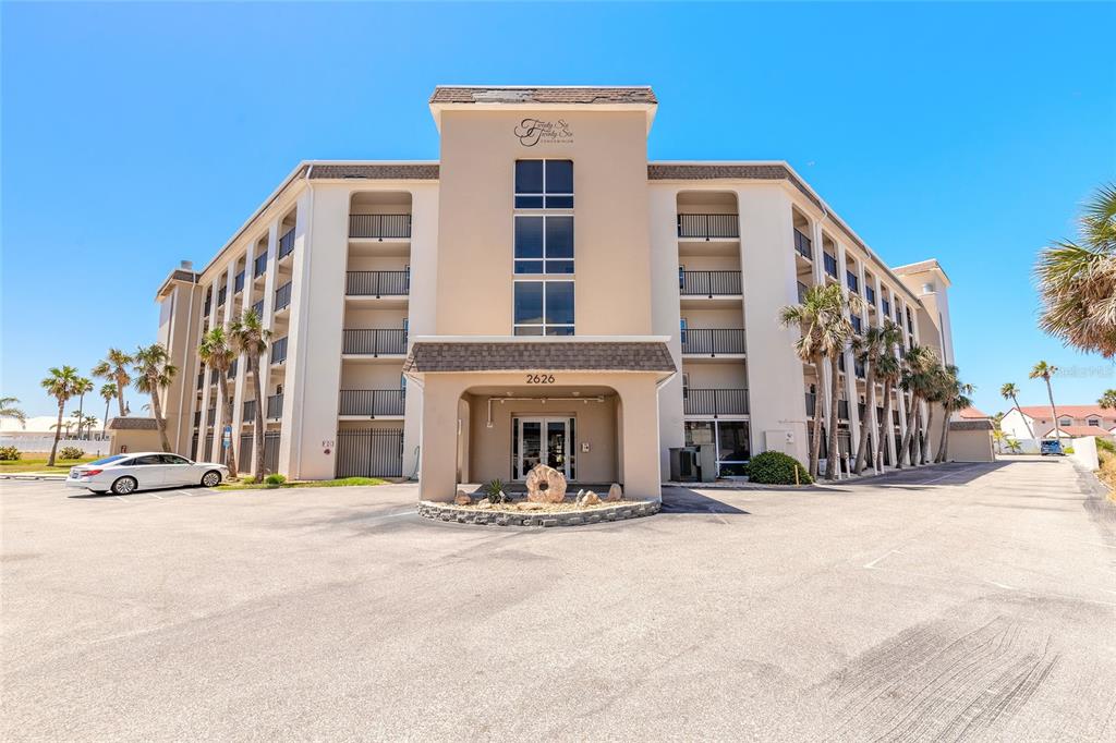 A multi-story beige condominium building with balconies and a parking lot in front — 2626 S ATLANTIC AVENUE UNIT 3020, DAYTONA BEACH SHORES, FL