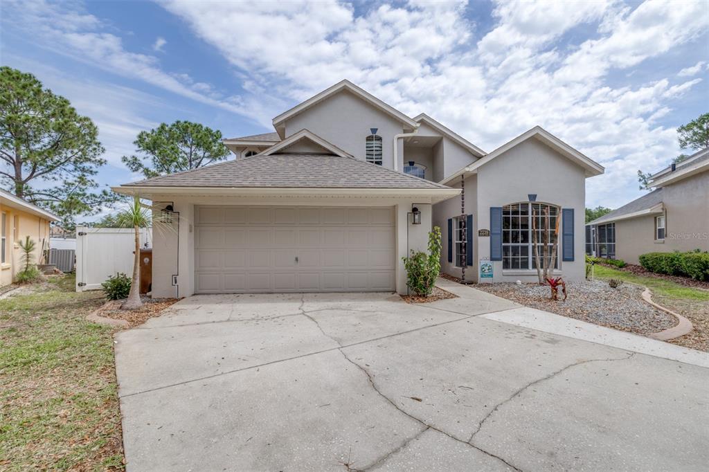A two-story house with a beige stucco exterior, a two-car garage, and a concrete driveway — 2239 MALLORY CIRCLE, HAINES CITY, FL