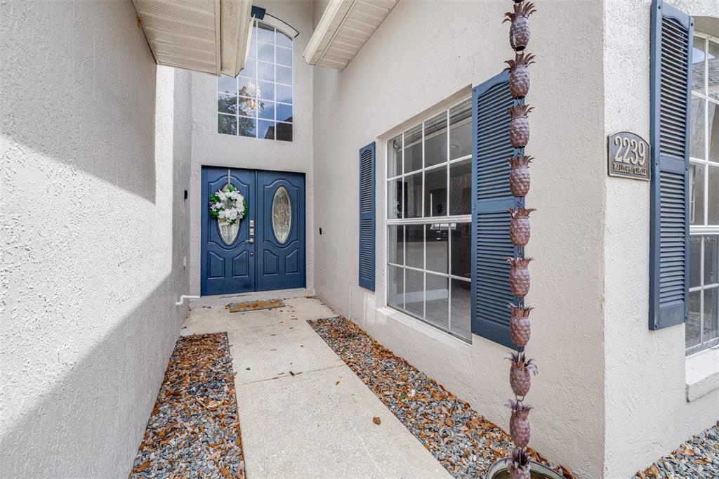 The exterior entrance features a double blue door, a pineapple rain chain, and shutters — 2239 MALLORY CIRCLE, HAINES CITY, FL
