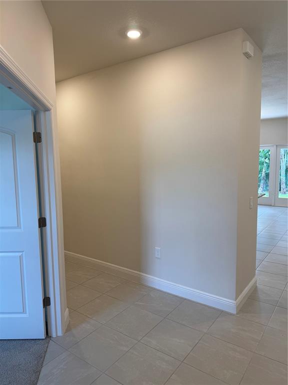 A tiled hallway leads toward a bright living area with glass doors — 3271 NADASKY AVENUE, NORTH PORT, FL